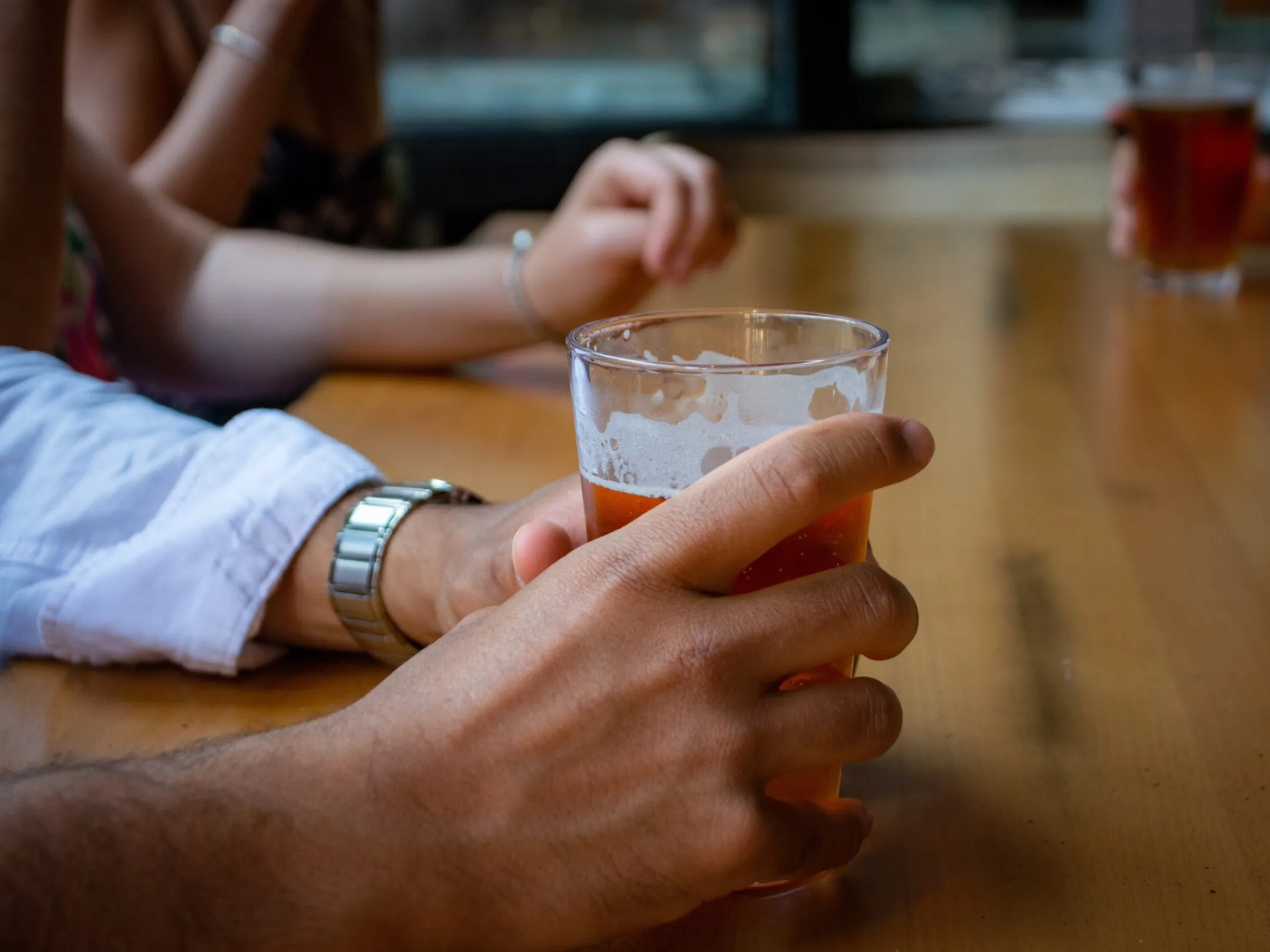 a hand holding a glass of beer on a table