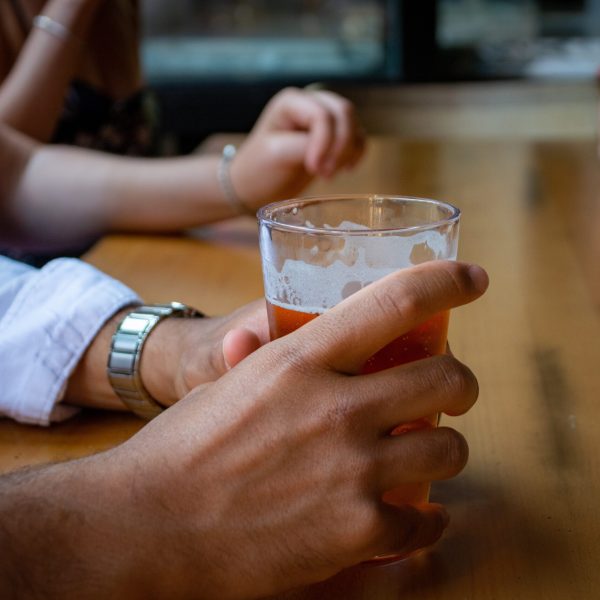 a hand holding a glass of beer on a table